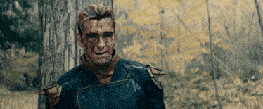 a man with blood on his face is standing in the woods