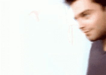 a blurry picture of a man 's face with a blue shirt on against a white background .