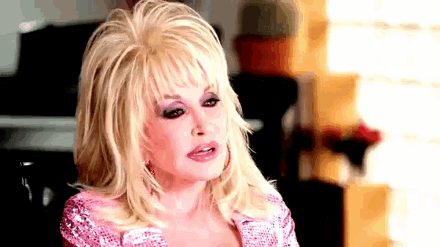 dolly parton is wearing a pink dress and looking at the camera with a serious look on her face .