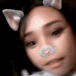 a close up of a woman wearing cat ears and a cat nose filter .