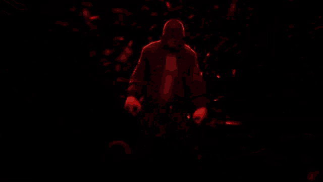 a man is standing in a dark room with red lights behind him