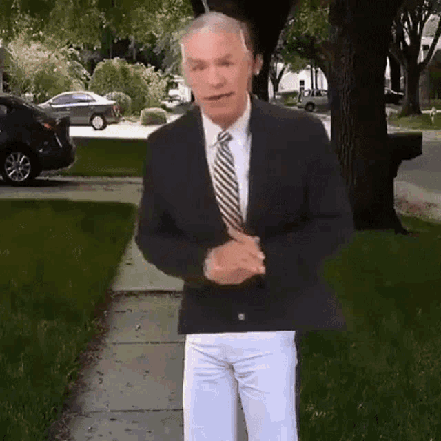 a man in a suit and tie is standing on the sidewalk