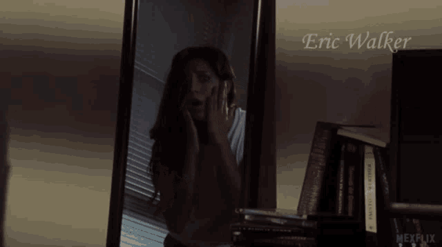 a woman is looking at herself in a mirror with the name eric walker on the bottom right
