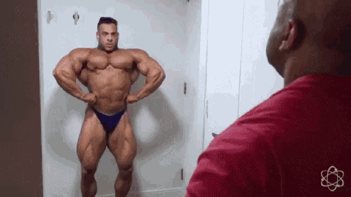 a man is standing in front of a mirror looking at his muscles .