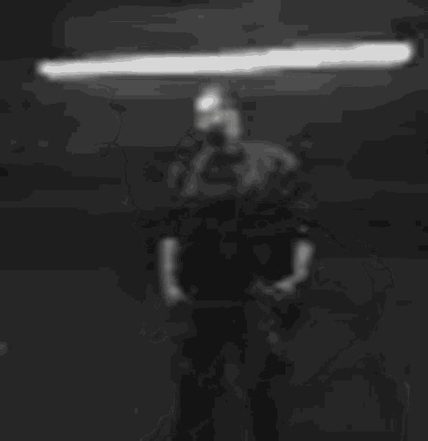a silhouette of a man standing with his hands on his hips in a black and white photo .