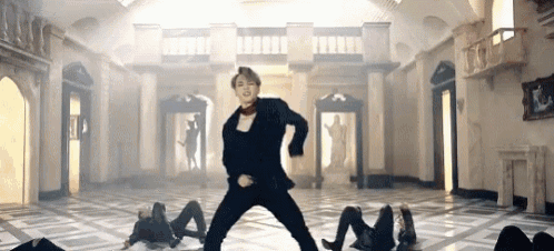 a man in a black suit is dancing in a room with a marble floor .