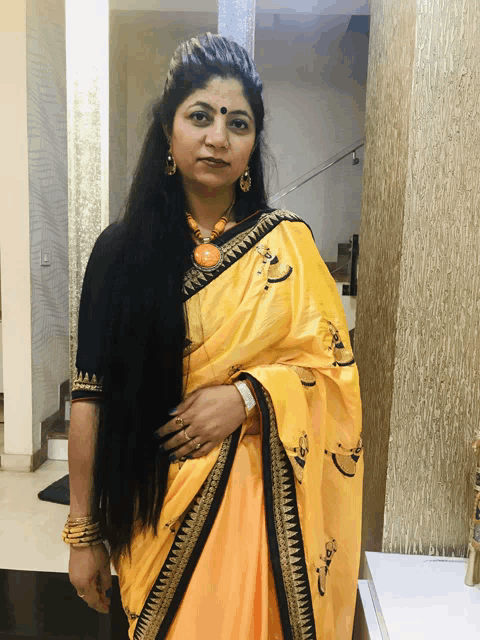 a woman wearing a yellow saree with black trim