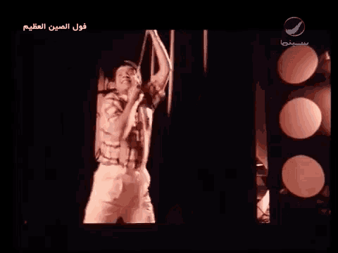 a man is singing into a microphone in a dark room