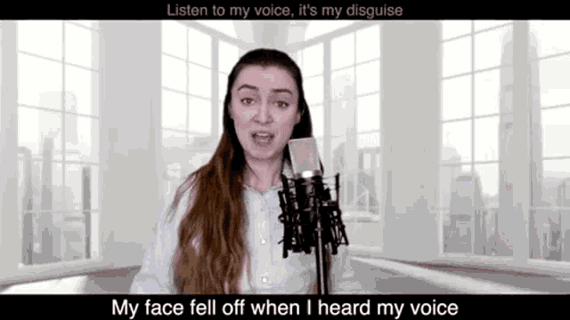 a woman is singing into a microphone in front of a window in a room .