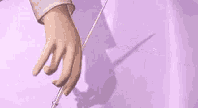 a person is holding a knife over a purple surface and cutting it .