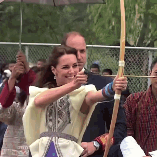 a woman is holding a bow and arrow and smiling at the camera