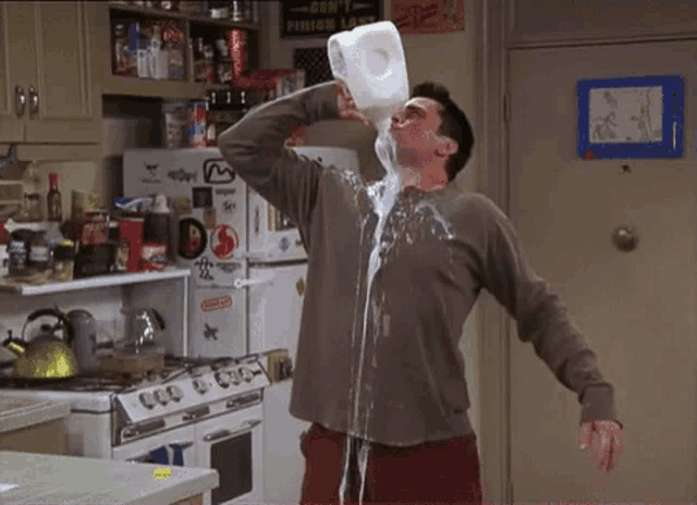 a man is pouring milk from a bottle into his face .