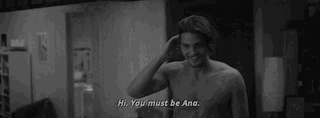 a black and white photo of a shirtless man talking to another shirtless man .