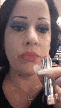 a close up of a woman 's face holding a bottle of lipstick