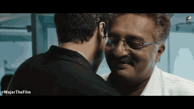 a man with glasses and a mustache is touching another man 's forehead with the words major the film below him