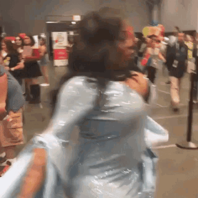 a woman in a blue dress is standing in a crowded room .