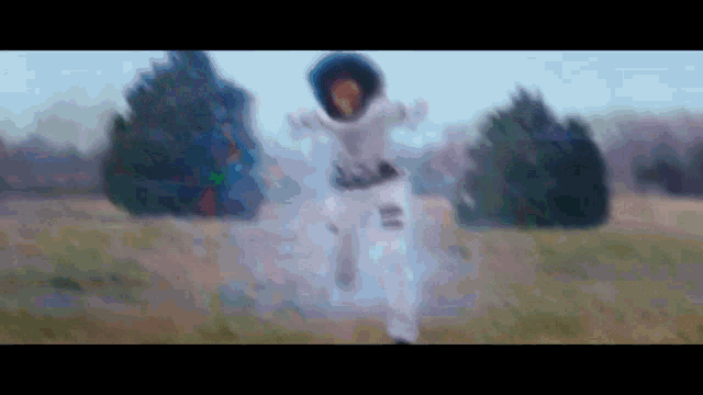 a blurry picture of a person in an astronaut costume running in a field