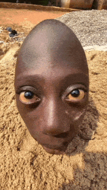a statue of a child 's face is buried in the sand