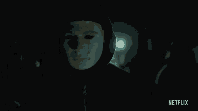 a person wearing a mask in a dark room with a netflix logo on the bottom right