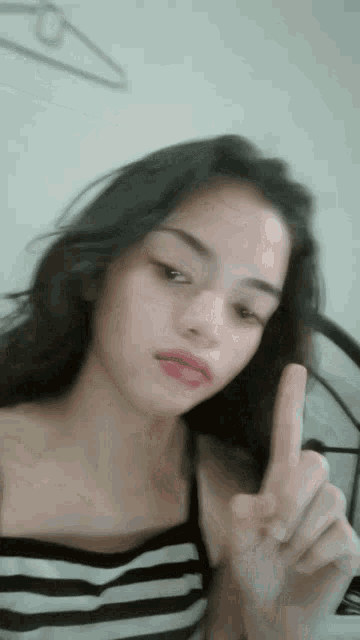 a woman in a black and white striped top is giving a peace sign