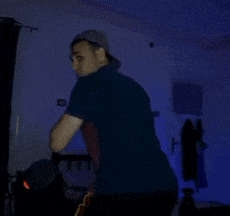 a man in a baseball cap is standing in a dark room with blue lights