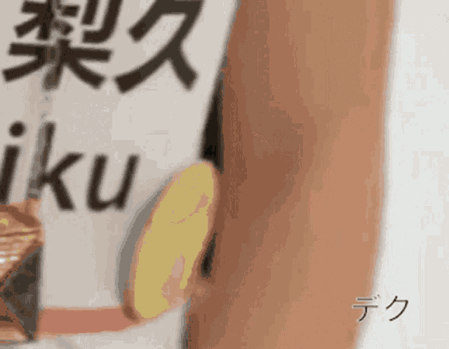 a person holding a piece of food in front of a sign that says ' iku '