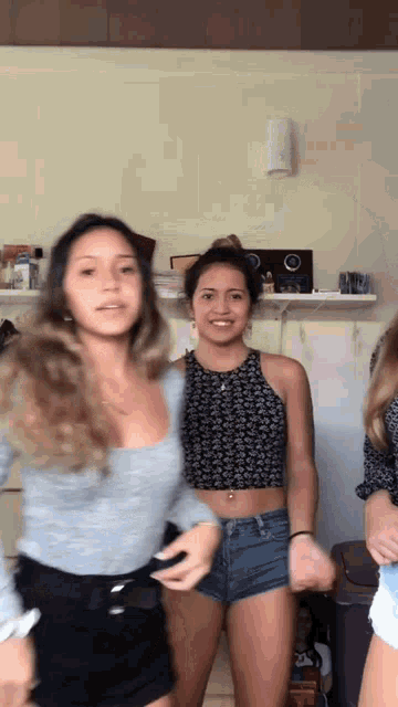 three young women are dancing together in a room .