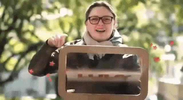 a woman wearing glasses is holding a cardboard box with the letter l on it ..