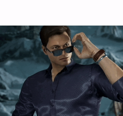 a man wearing sunglasses and a blue shirt adjusts his sunglasses