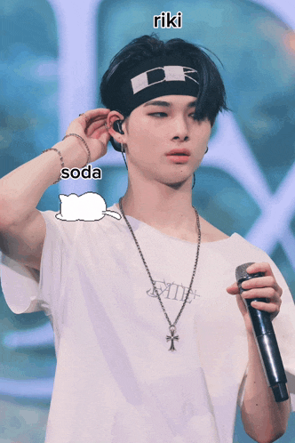 a young man is holding a microphone and wearing a headband with the word riki written on it