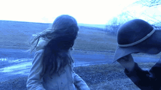 a woman in a trench coat and a man in a hat are standing next to each other