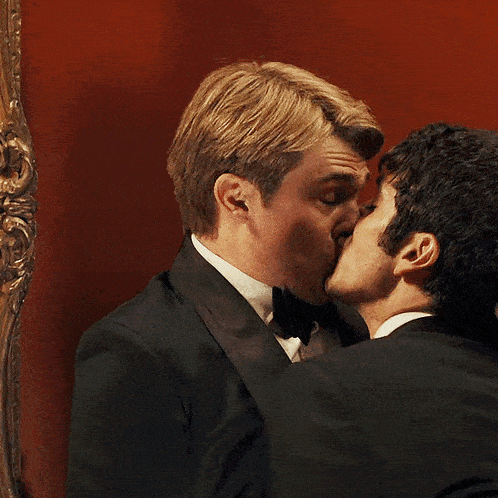 a man with a ring on his finger kissing another man