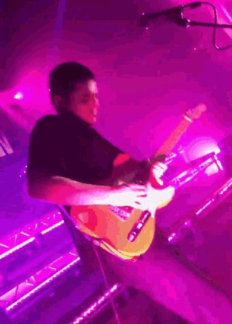 a man playing a guitar in a dark room
