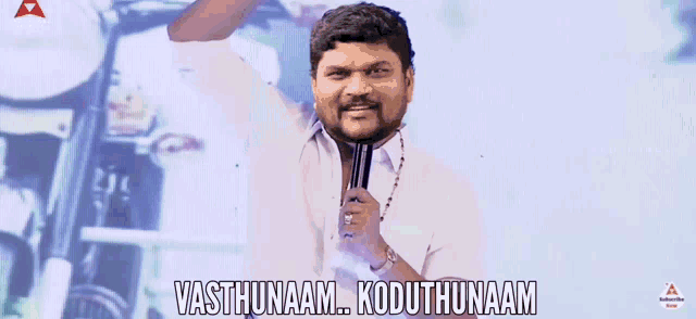 a man in a white shirt is holding a microphone and says vasthunaam