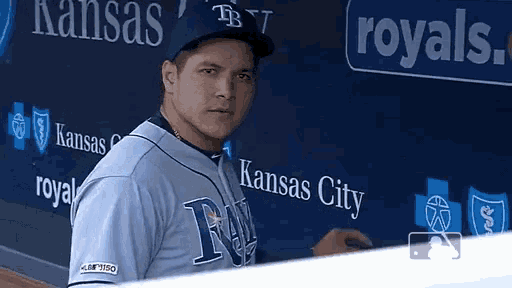 a baseball player stands in front of a wall that says kansas city on it