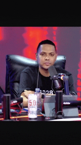 a man sitting in front of a microphone with a can of public 5.0 on the table