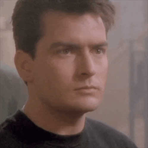 a close up of a man 's face in a black shirt looking at the camera .