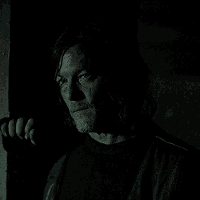 a man is standing in a dark room with his eyes closed