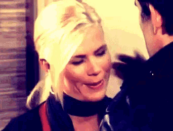 a man and a woman are standing next to each other and the woman is wearing a black scarf around her neck .