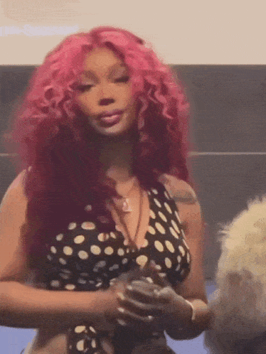 a woman with pink hair is wearing a polka dot top .