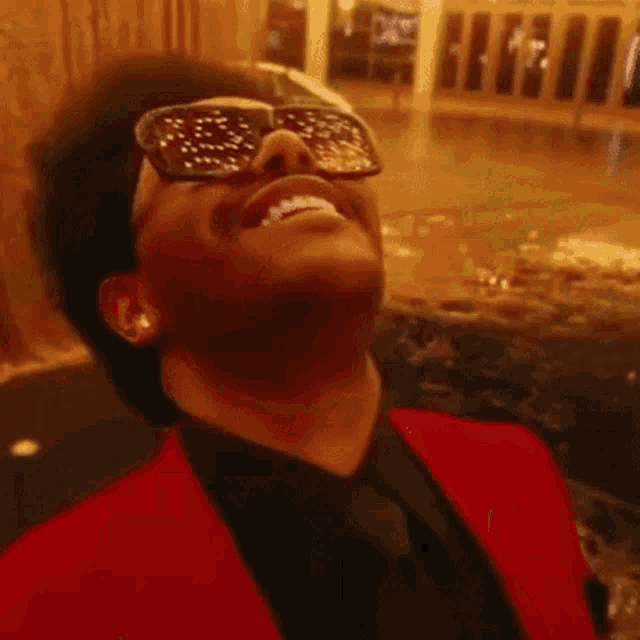a close up of a man wearing sunglasses and laughing with his mouth open .
