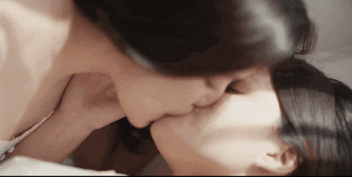two women kissing each other on a bed