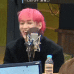 a person with pink hair is sitting in front of a microphone