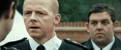 a man in a police uniform is talking to another man in a suit