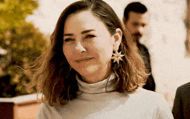 a woman wearing a turtleneck and earrings with a star on it