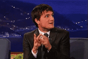 a man in a suit is clapping his hands together