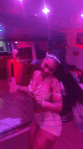 a woman is standing in a room with purple lights and holding a phone .