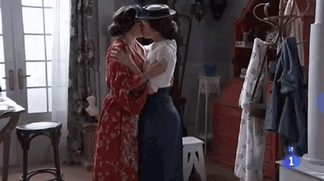 two women are kissing in a room with the number 1 in the corner