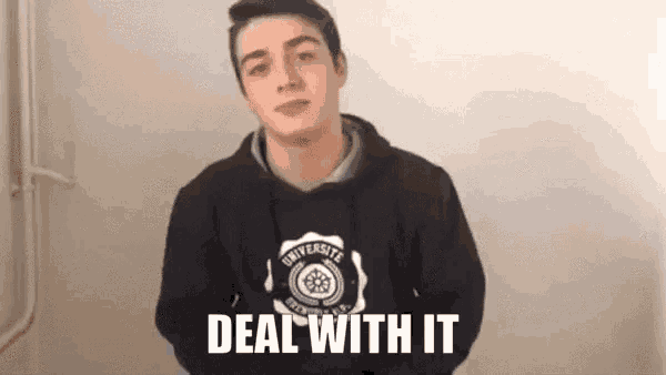 a young man wearing a black hoodie is standing in front of a wall .