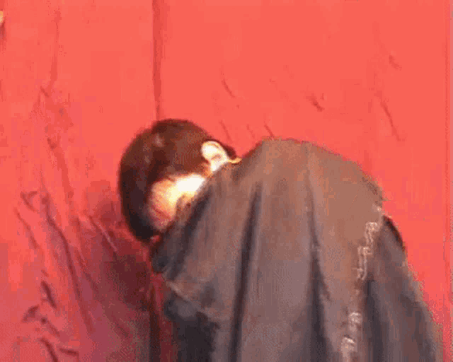 a young man is laying on a red couch with his legs crossed and looking at the camera .